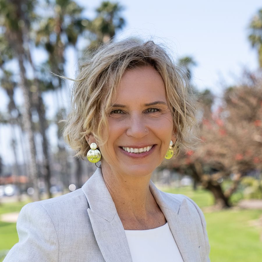 Michelle Grossman smiling warmly, hands on hips, palm trees behind her